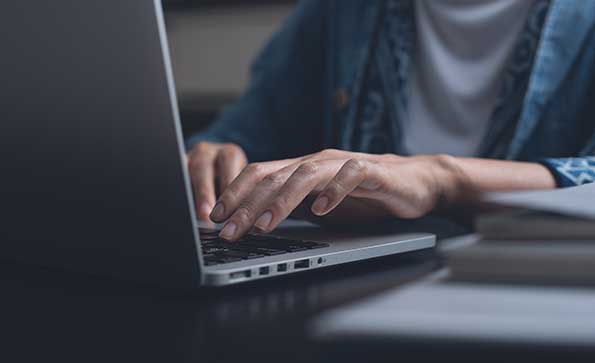 Woman online working on laptop computer at night from home office
